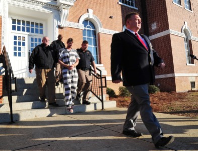 Telfair County Sheriff Chris Steverson walks in front of Ronnie Adrian “Jay” Towns as Towns is lead from the courthouse to a waiting sheriff's cruiser. Towns has been charged with murder and armed robbery in the deaths of Bud and June Runion, according to Telfair County Sheriff Steverson.